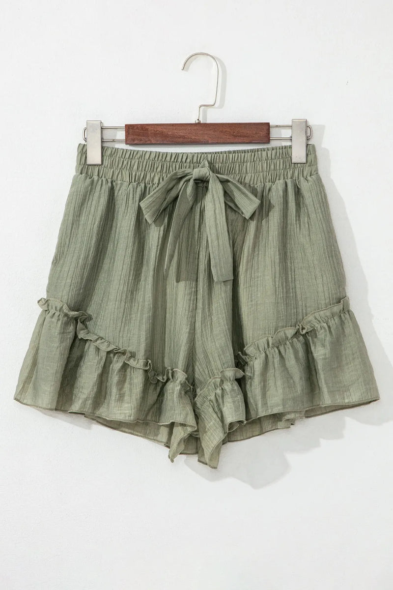 Green ruffled shorts on a hanger against a white background