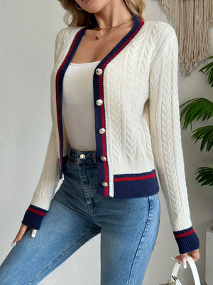 Woman wearing a white cardigan with blue and red trim, paired with blue jeans.