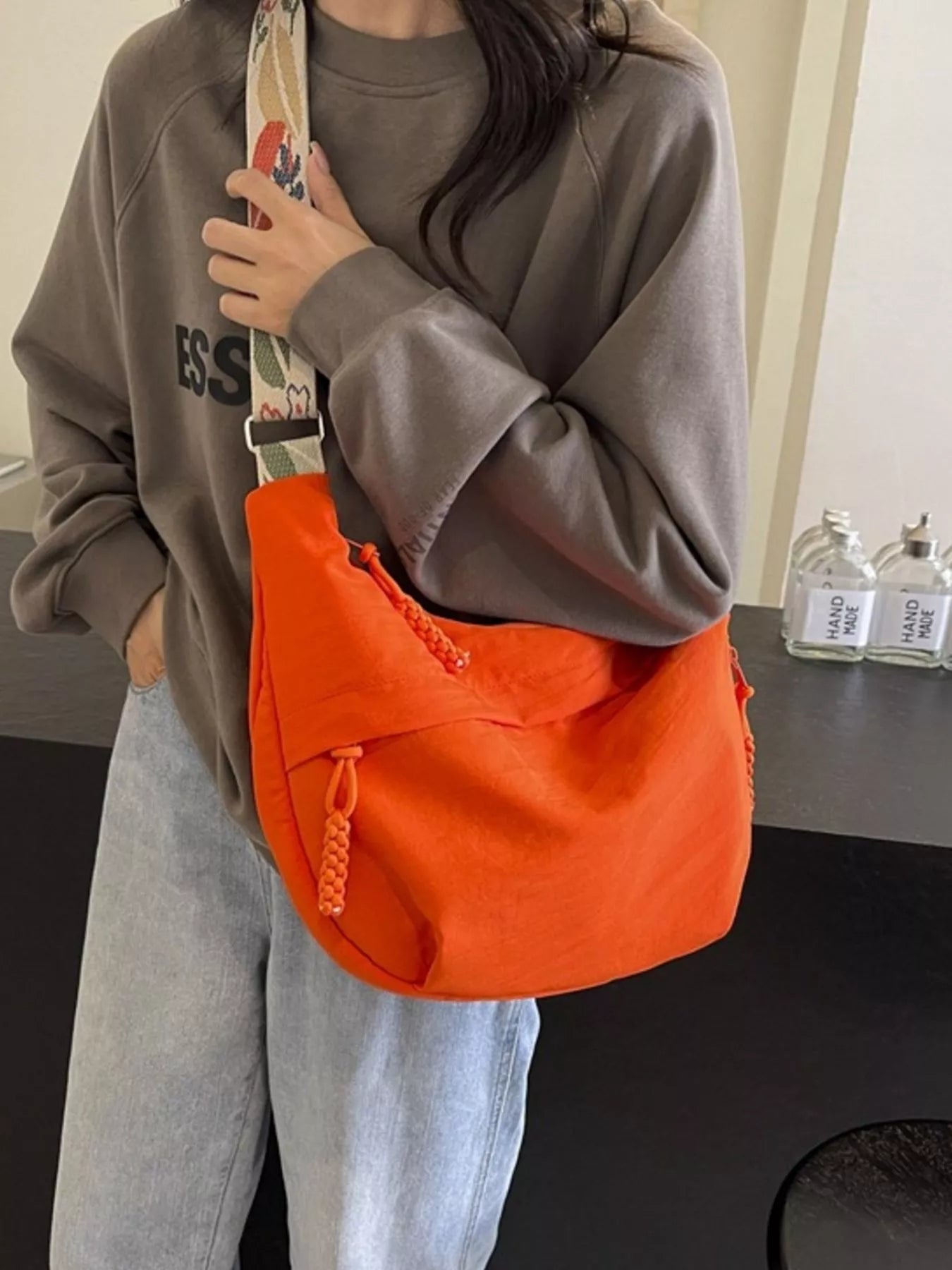 Person wearing an orange shoulder bag with a neutral background