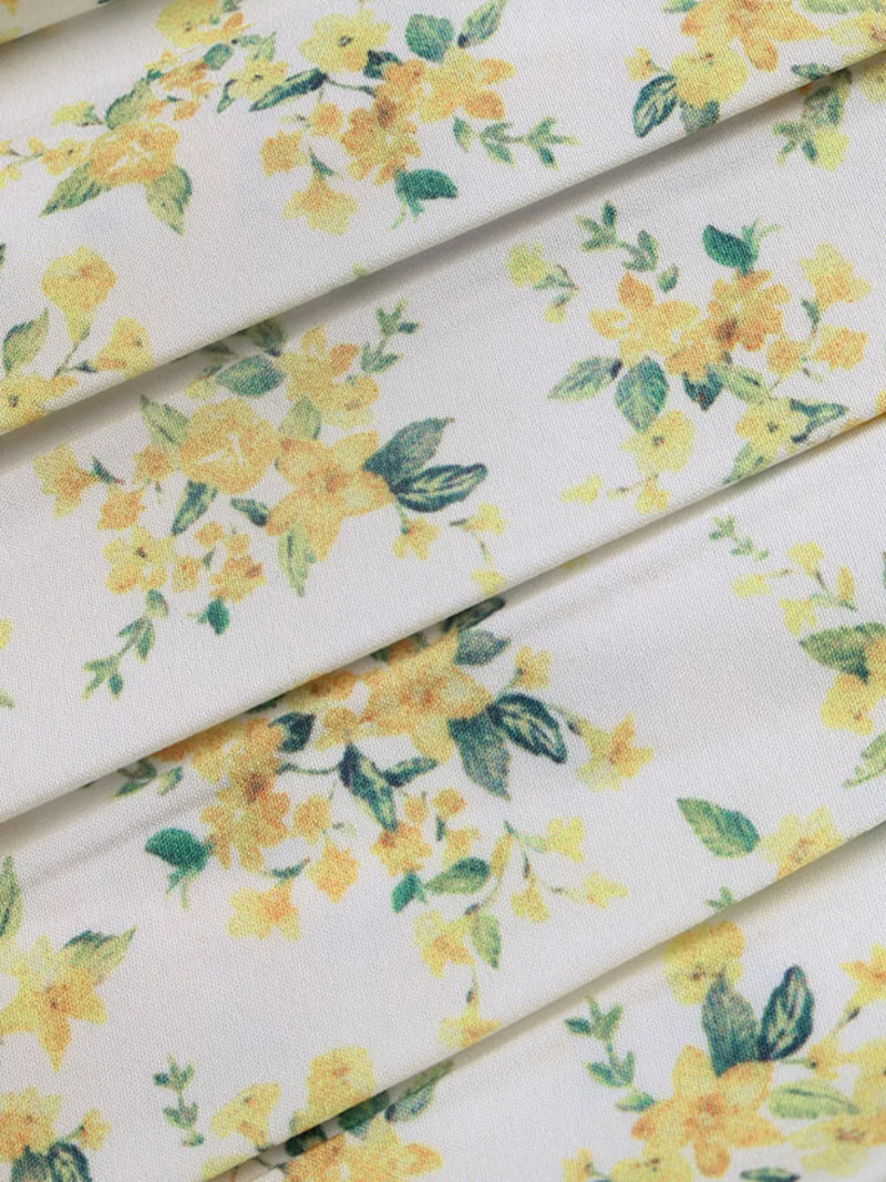 Floral fabric with yellow flowers and green leaves on a white background