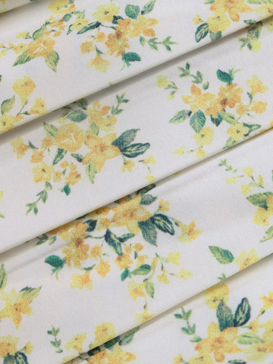 Floral fabric with yellow flowers and green leaves on a white background