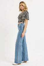 Woman wearing a zebra print top and blue jeans on a white background