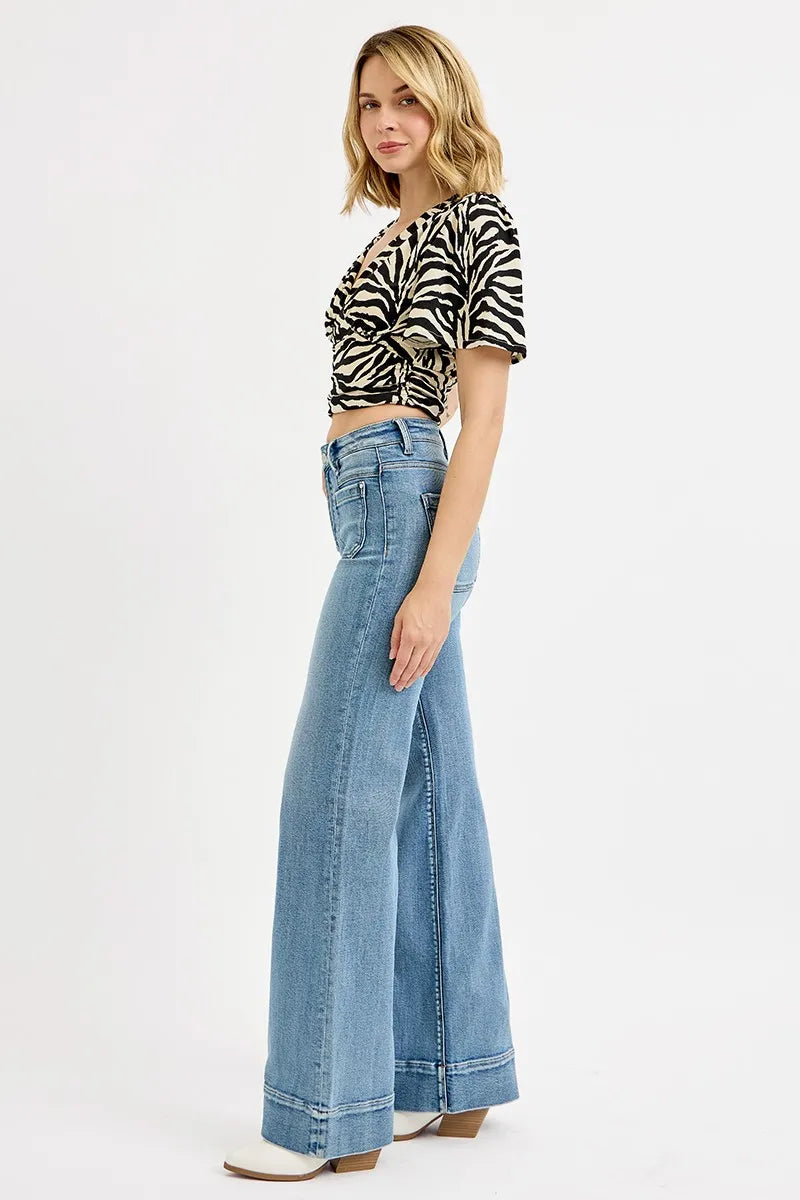 Woman wearing a zebra print top and blue jeans on a white background