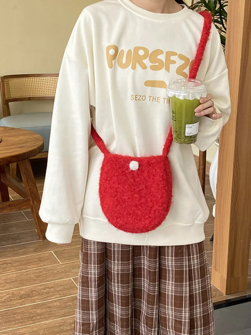 Person wearing a white sweatshirt with 'PURSFZ' text, holding a red bag and a green drink.
