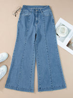 Blue jeans on a beige surface with white sneakers and a magazine.