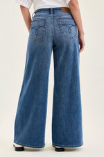 Person wearing blue wide-leg jeans on a white background