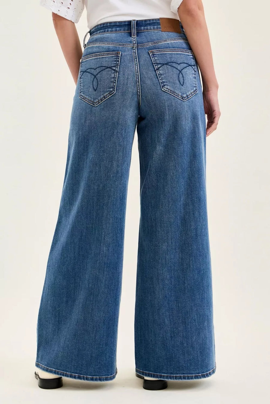 Person wearing blue wide-leg jeans on a white background