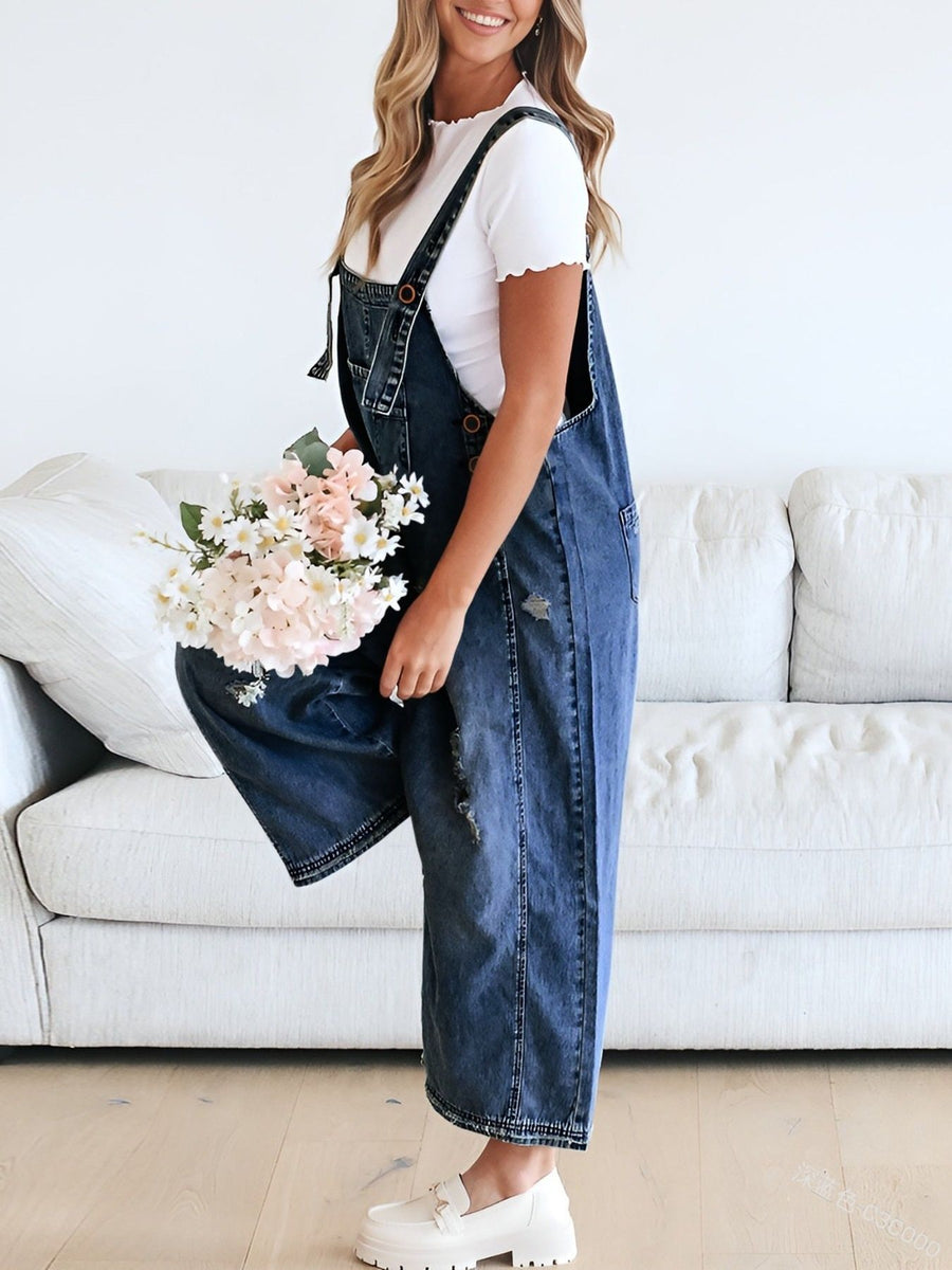 Person wearing denim overalls holding flowers in a living room setting