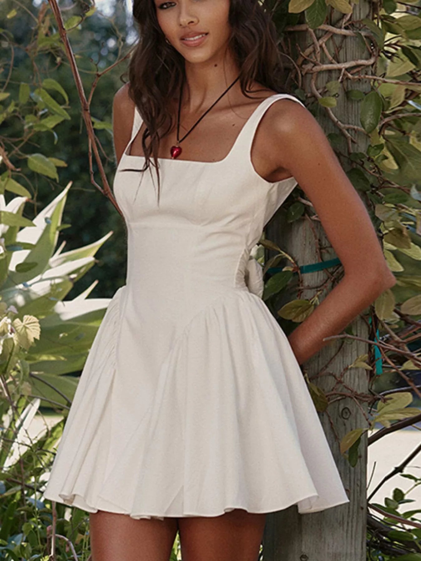 Woman wearing a white dress standing among green foliage