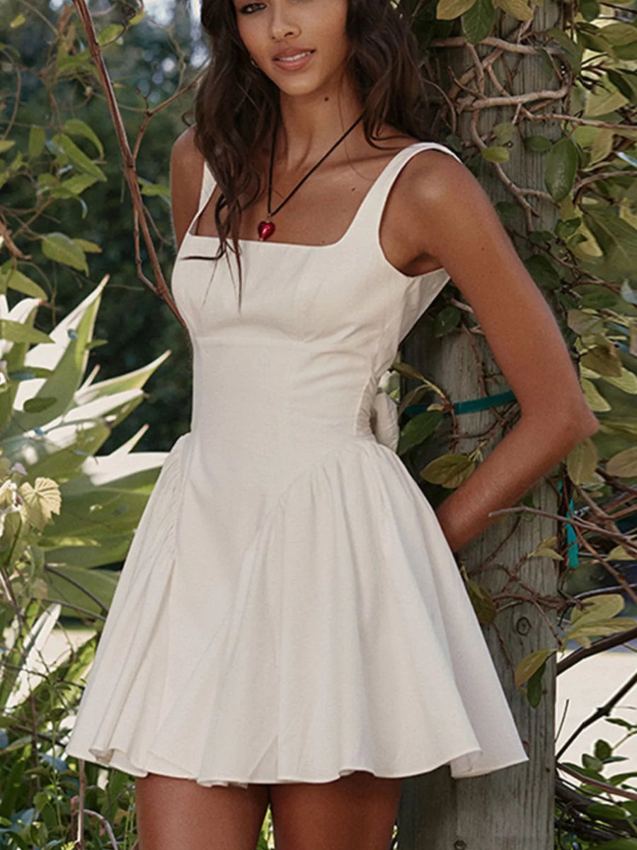 Woman wearing a white dress standing among green foliage