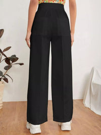 Person wearing black wide-leg pants with a white background