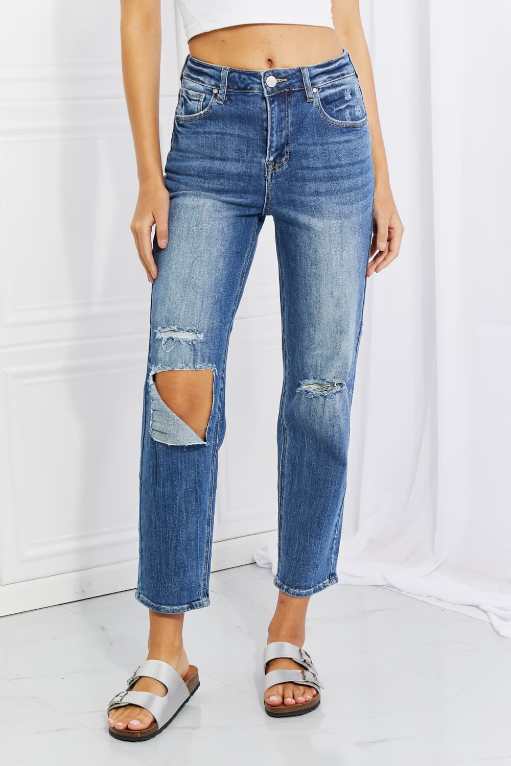 Person wearing distressed blue jeans on a white background
