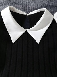 Black dress with a white collar on a textured gray background