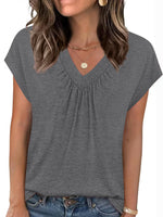 Woman wearing a gray short-sleeve top with a plain background
