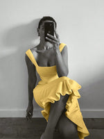 Person wearing a yellow dress sitting against a plain wall.