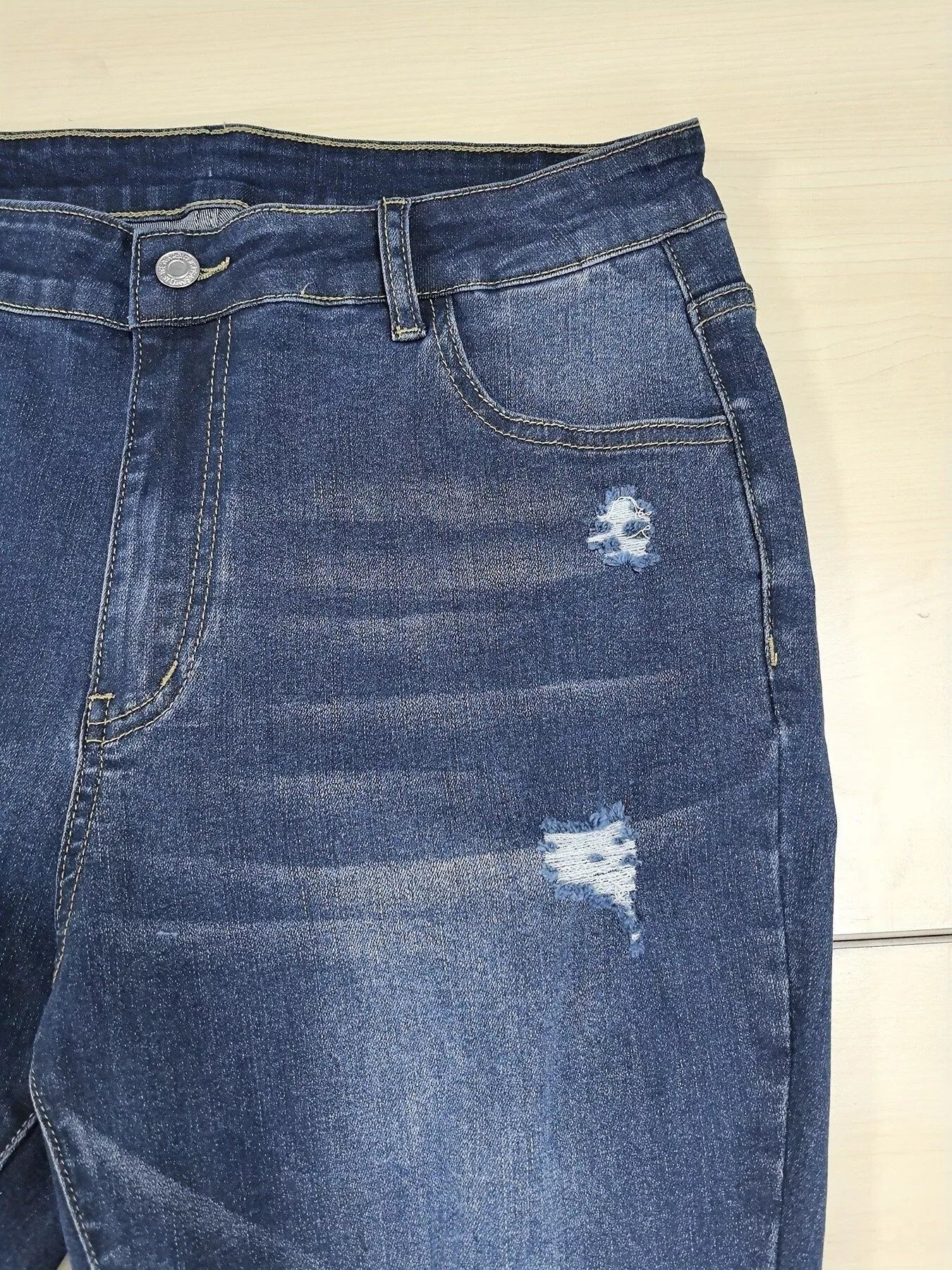 Blue denim jeans with distressing on a beige background