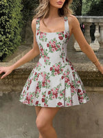 Woman wearing a floral dress standing outdoors with greenery in the background