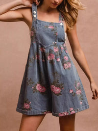 Denim pinafore dress with floral pattern worn by a person on a beige background