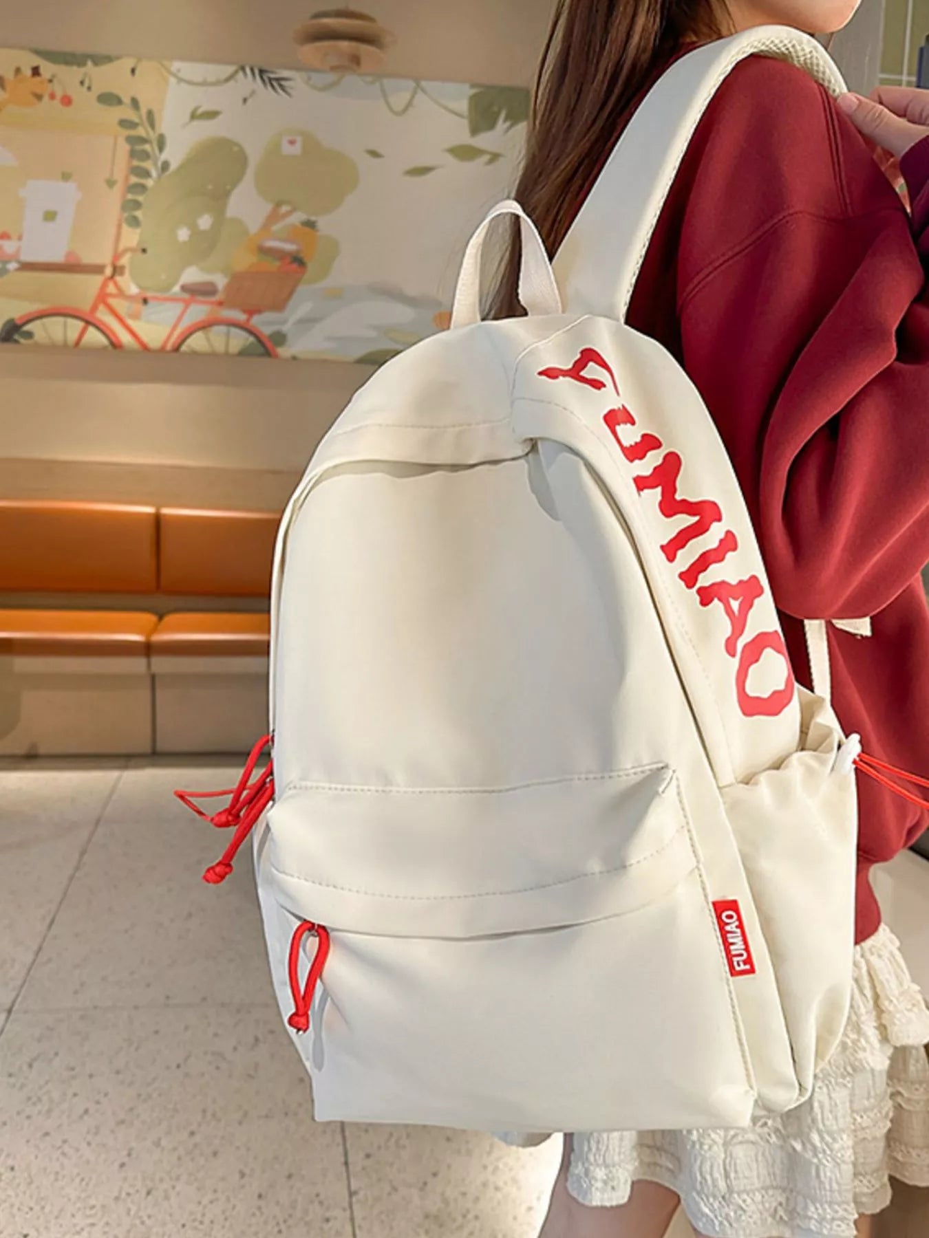 Person wearing a white backpack with red text in an indoor setting