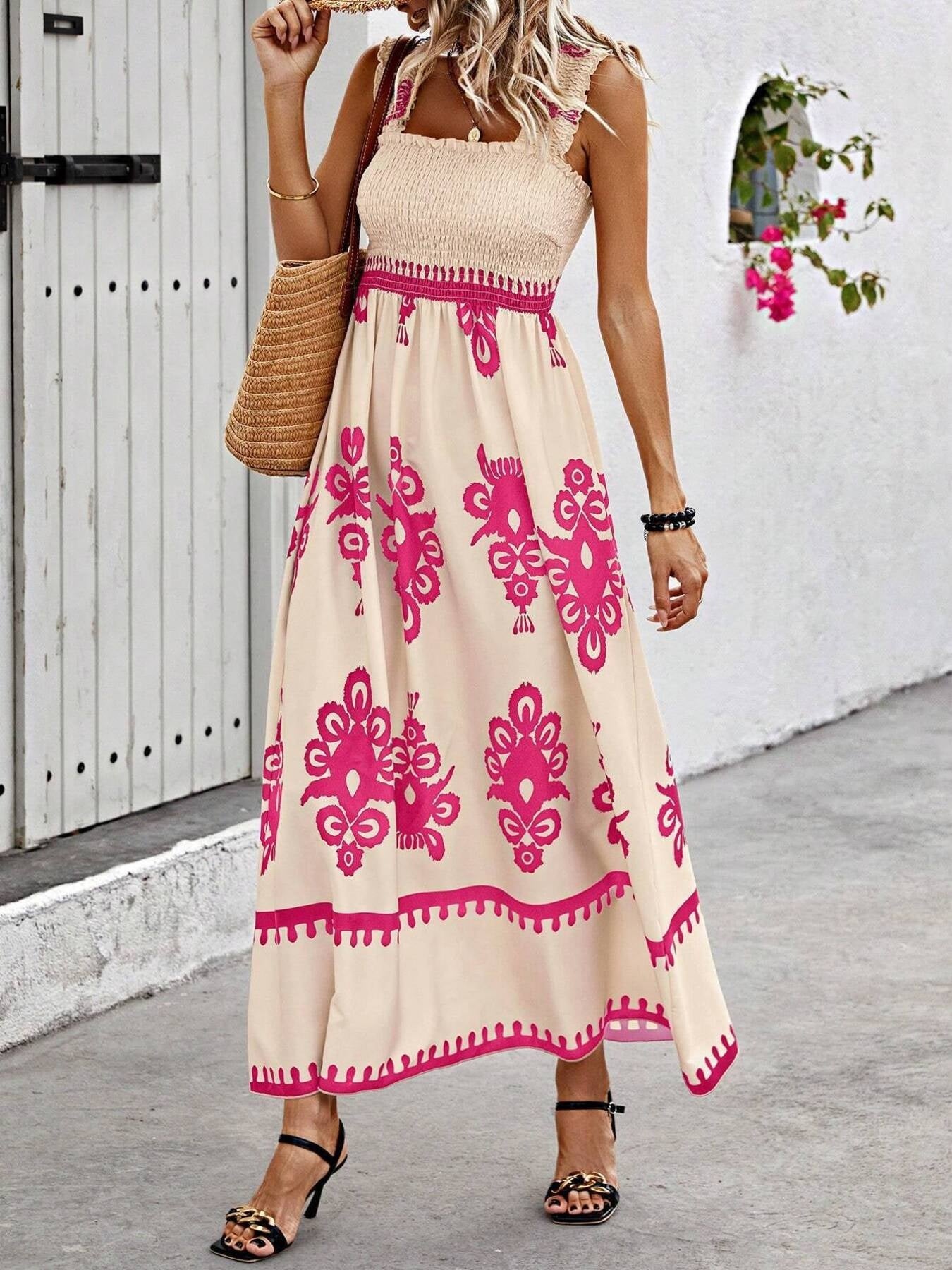 Woman wearing a beige dress with pink patterns, standing against a white wall.