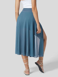 Woman wearing a blue skirt with a white top on a light gray background