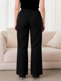 Person wearing black pants standing in a room with a beige sofa.