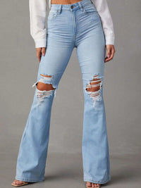 Light blue flared jeans with distressed details on a gray background