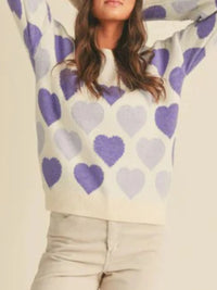 Person wearing a sweater with purple hearts on a beige background