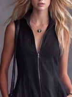 Woman wearing a black sleeveless top with a zipper, holding a purple handbag.