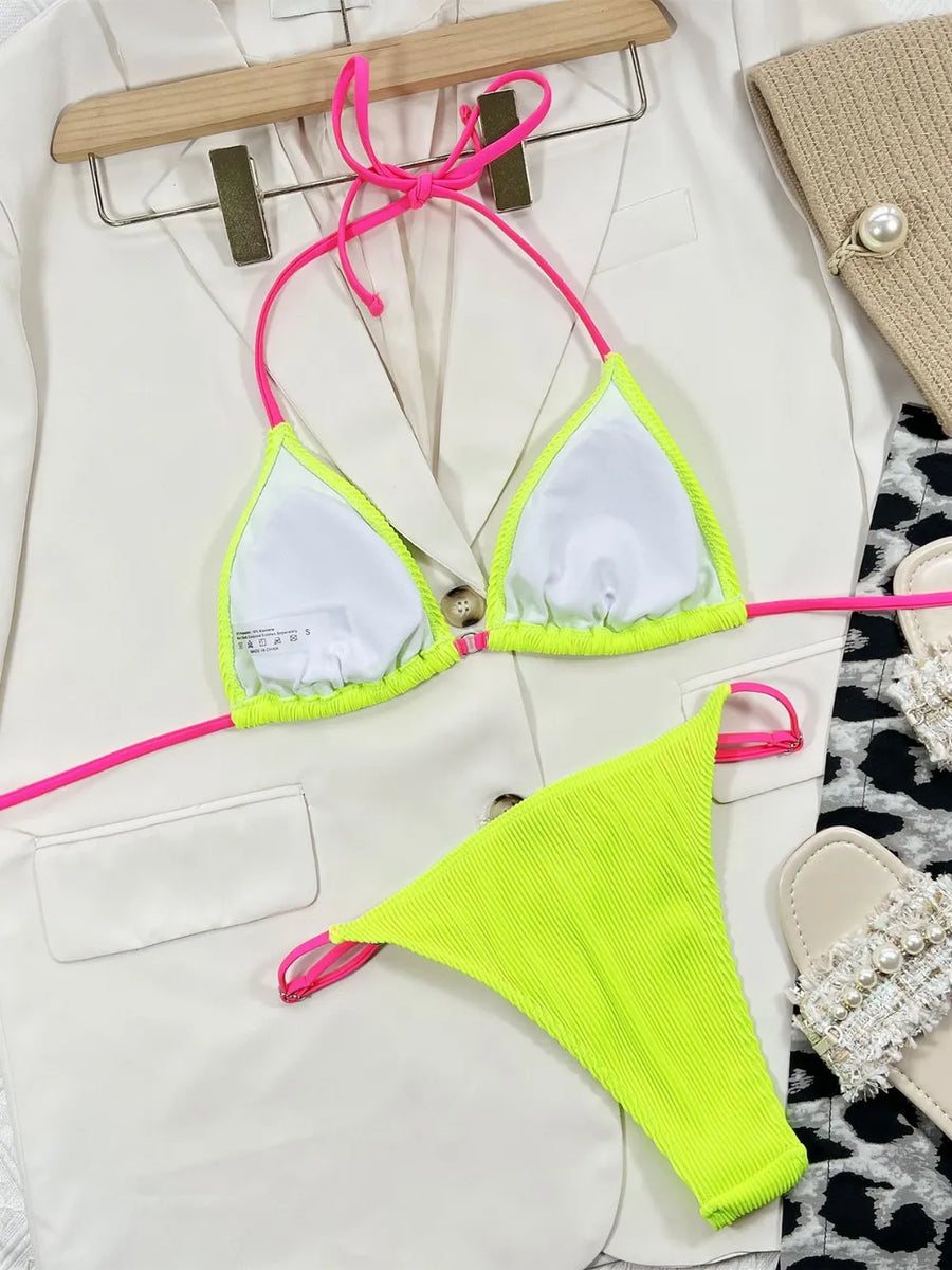 Neon green bikini with pink straps on a hanger against a white background