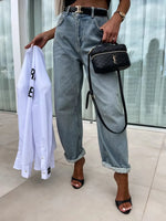 Person holding a white shirt and black handbag with a blurred background