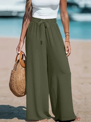 Person wearing olive green wide-leg pants on a beach