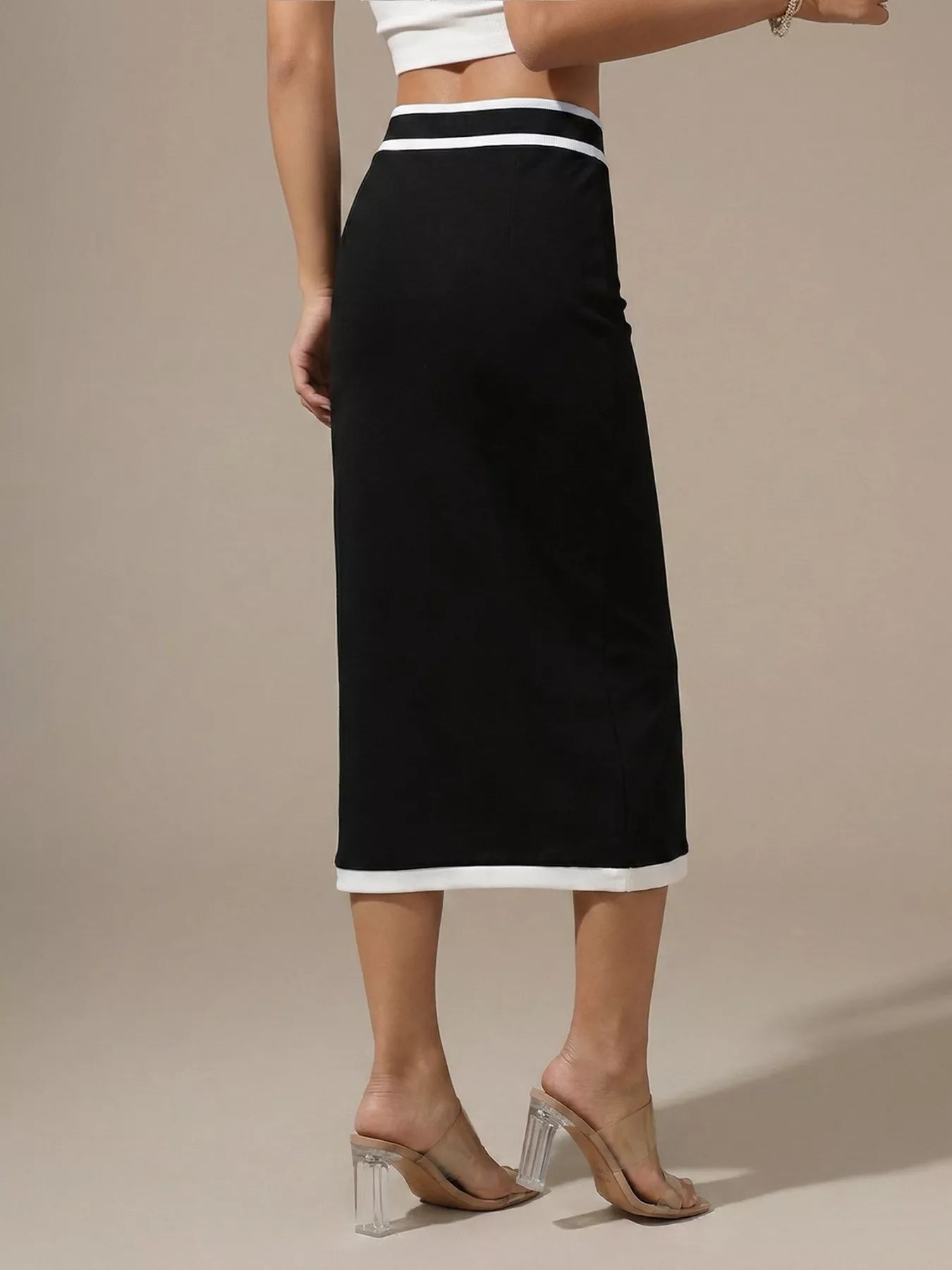 Black skirt with white trim worn by a person on a beige background