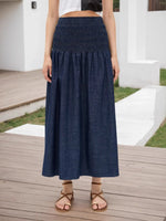 Person wearing a blue denim skirt on a wooden deck.