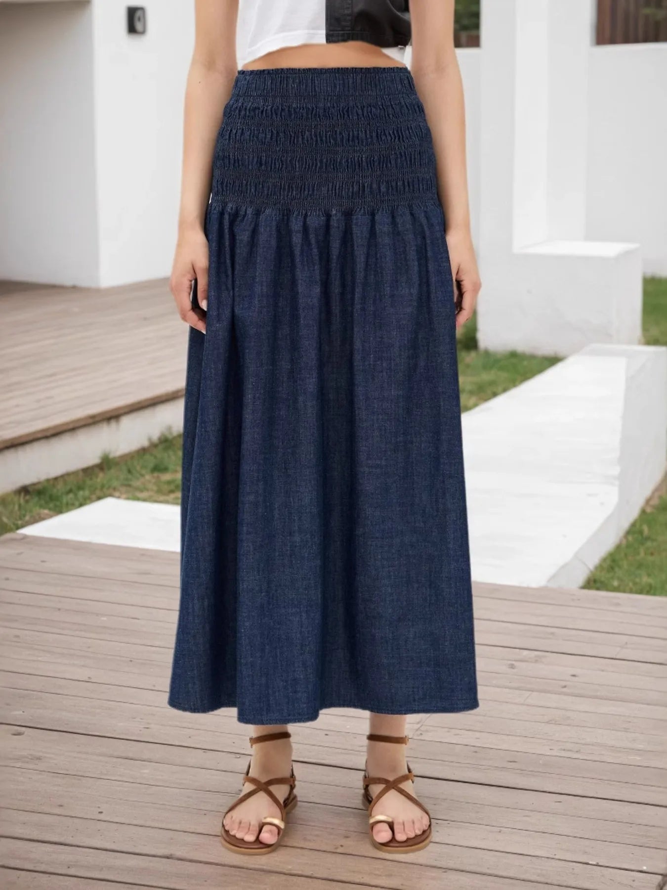Person wearing a blue denim skirt on a wooden deck.