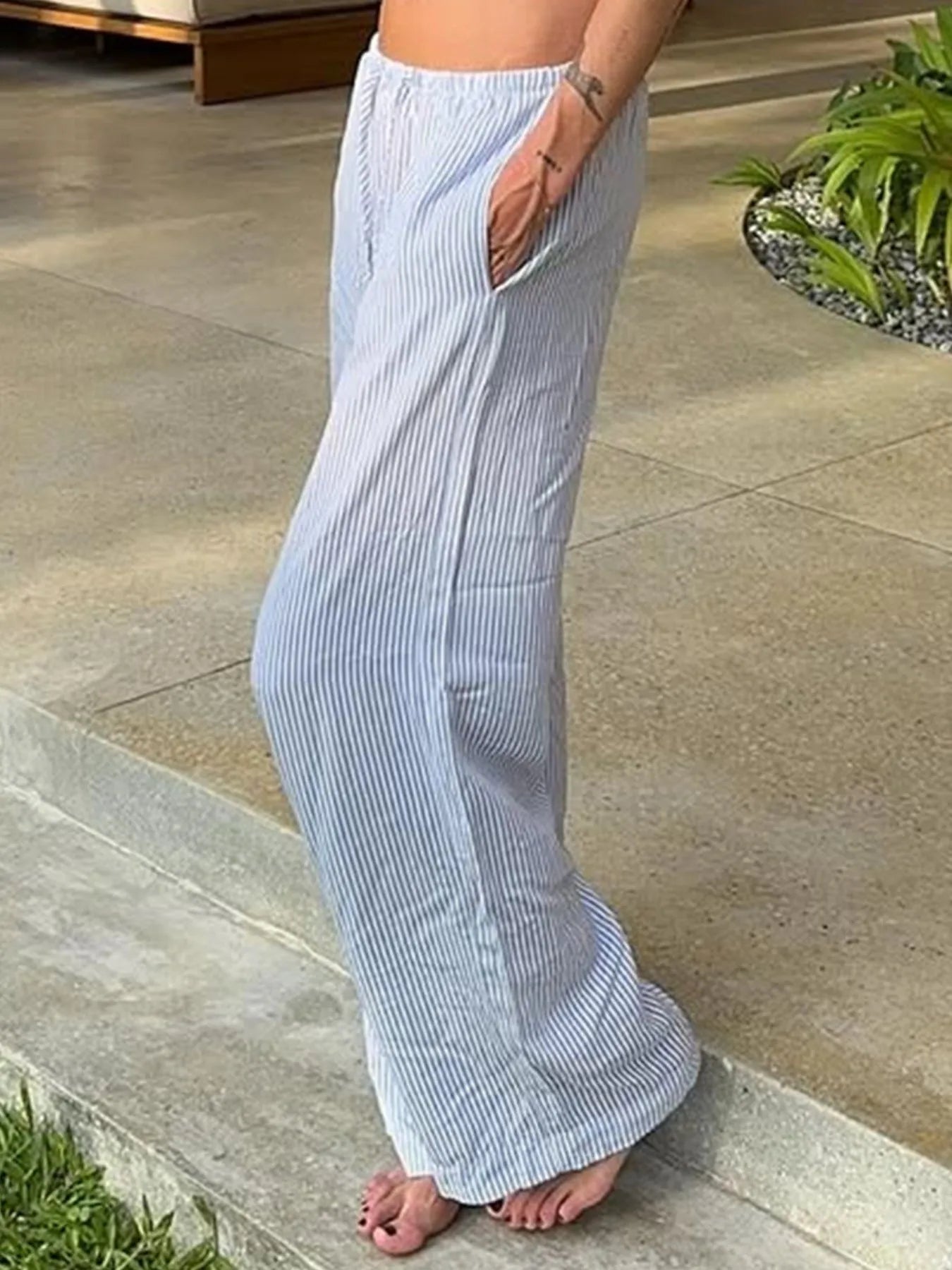 Person wearing light blue striped pants standing on a stone patio.