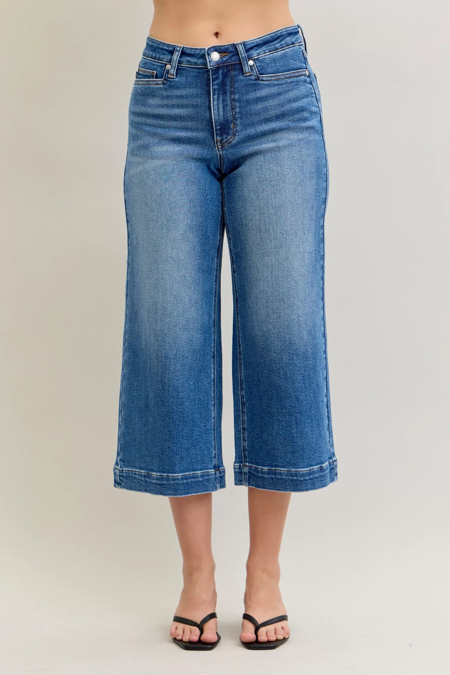 Blue jeans worn by a person on a plain background
