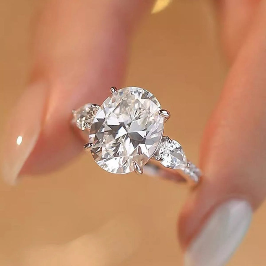 Diamond ring held between fingers with a blurred background
