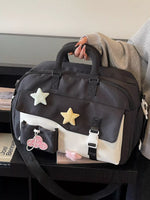 Black duffel bag with star and heart designs held by a person.