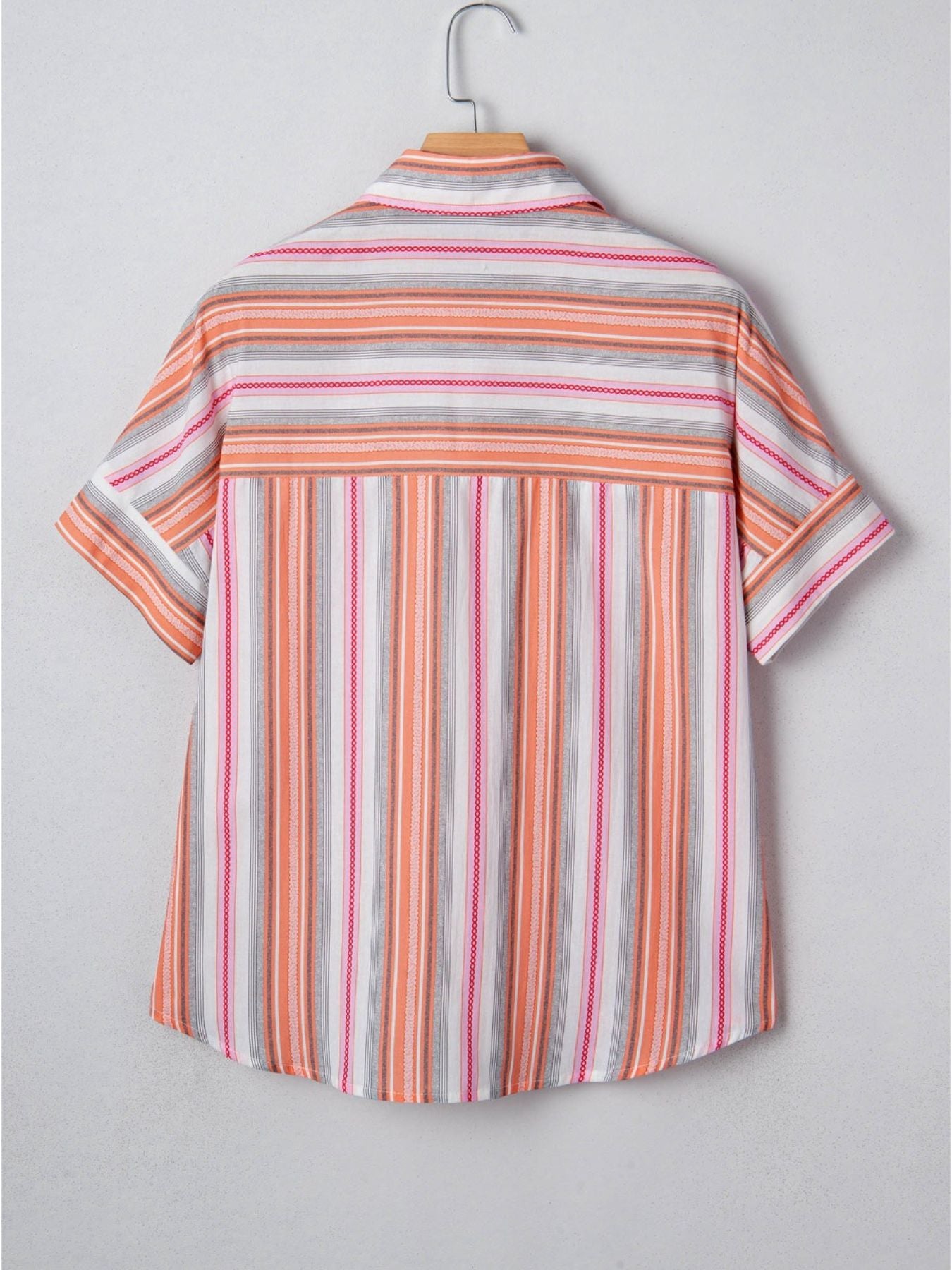Striped shirt on a hanger against a plain background