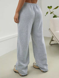 Person wearing gray sweatpants in a minimal indoor setting