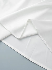Close-up of white fabric with a subtle pattern on a light gray background