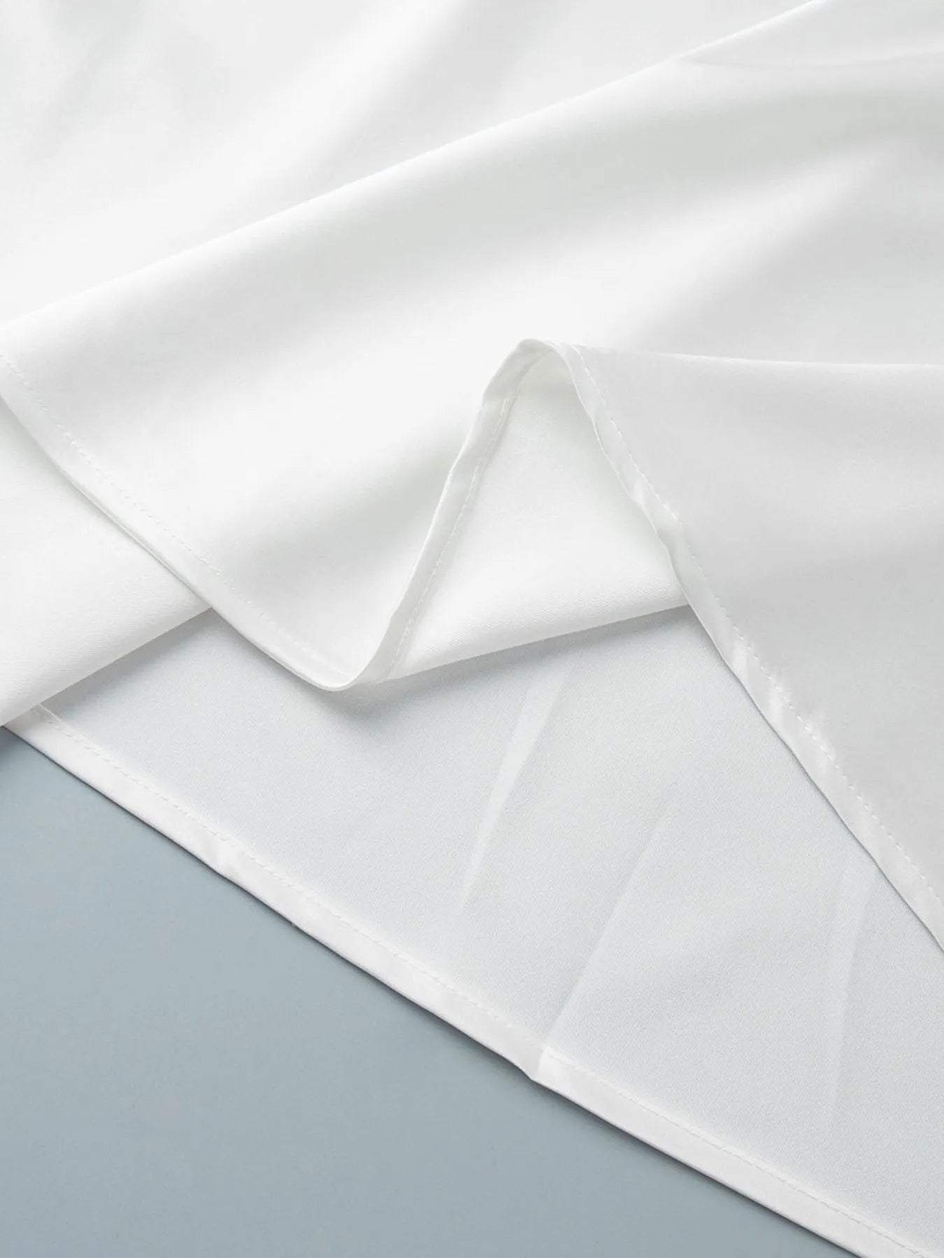 Close-up of white fabric with a subtle pattern on a light gray background