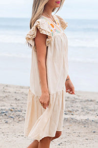 right Side view of woman on the beach in a beige dress