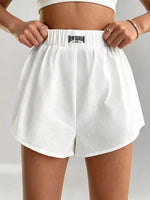 White shorts with a brand logo on a neutral background