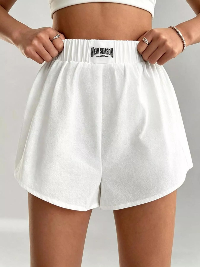 White shorts with a brand logo on a neutral background