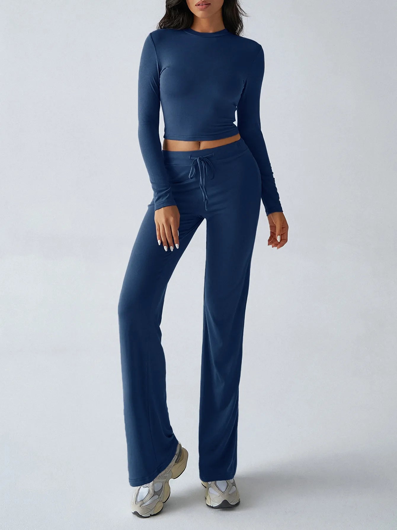 Person wearing a blue long-sleeve top and flared pants on a white background