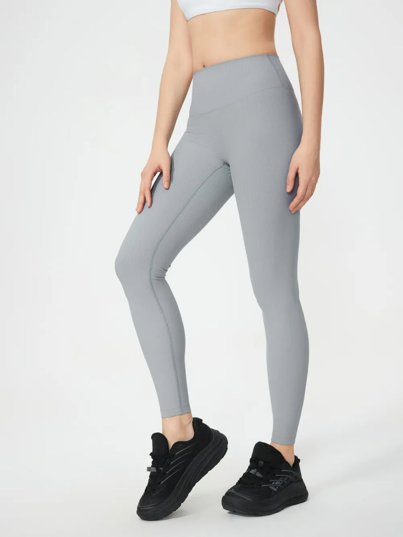 Person wearing gray leggings and black sneakers on a white background
