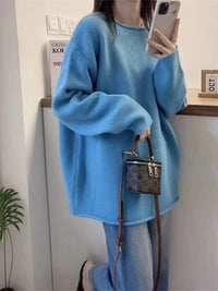 Person wearing a blue sweater holding a handbag indoors.