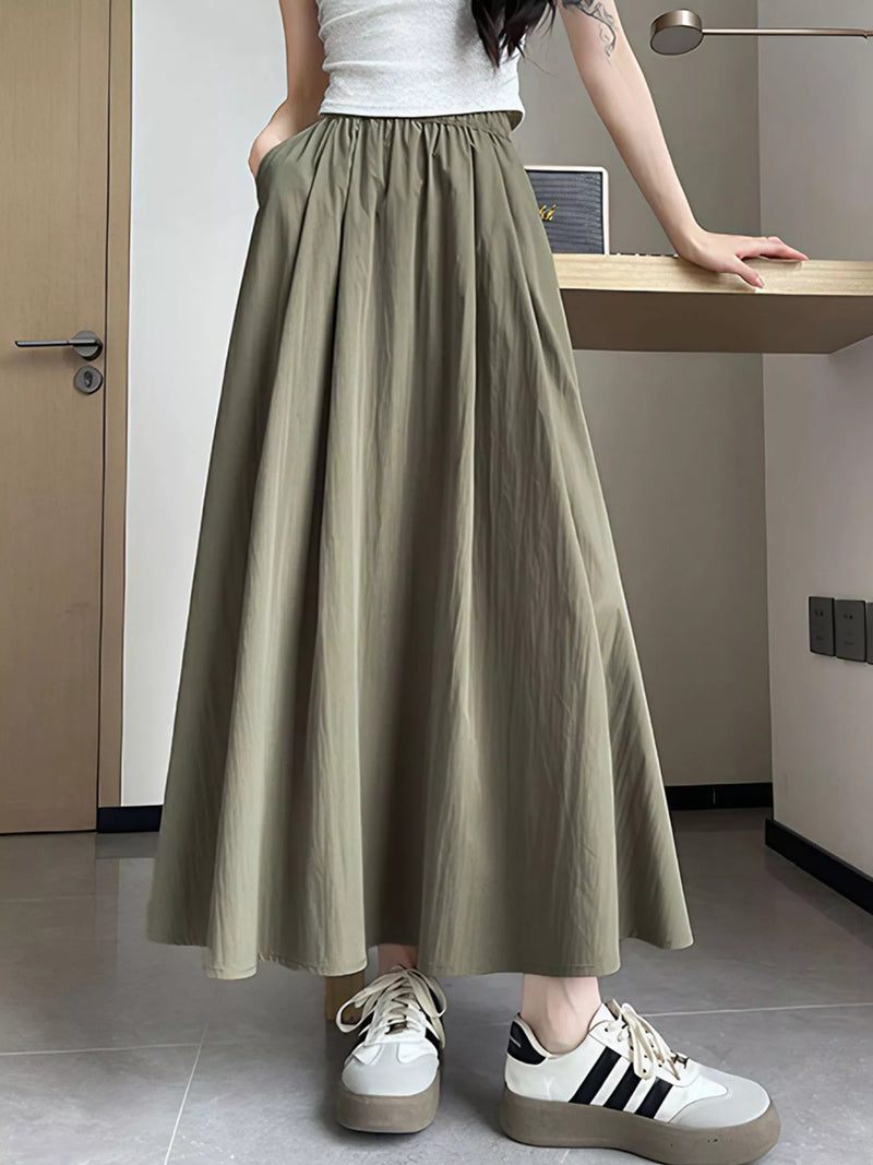 Person wearing a long olive green skirt with white sneakers in an indoor setting.
